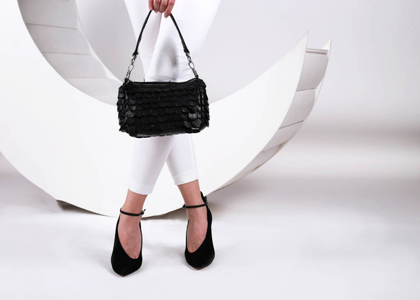 black sandals on the feet of a young girl.and black handbag in h - Foto, Imagem