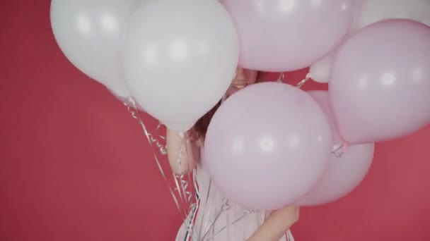 birthday, Valentines day concept. Happy girl holding a bunch of balloons on a red background, the girl is happy - Felvétel, videó