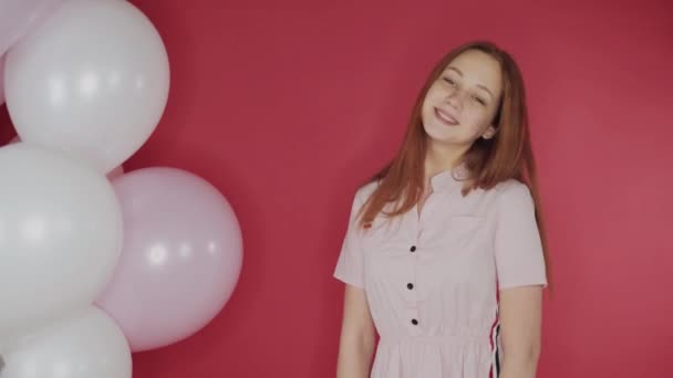 birthday, Valentines day concept. Happy girl holding a bunch of balloons on a red background, the girl is happy - Video, Çekim