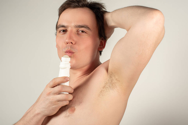 Handsome man with armpits holding a roll-on deodorant in his han - Photo, Image