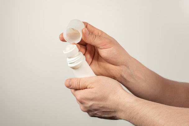 Manos masculinas sosteniendo desodorante para axilas sobre fondo blanco
 - Foto, Imagen