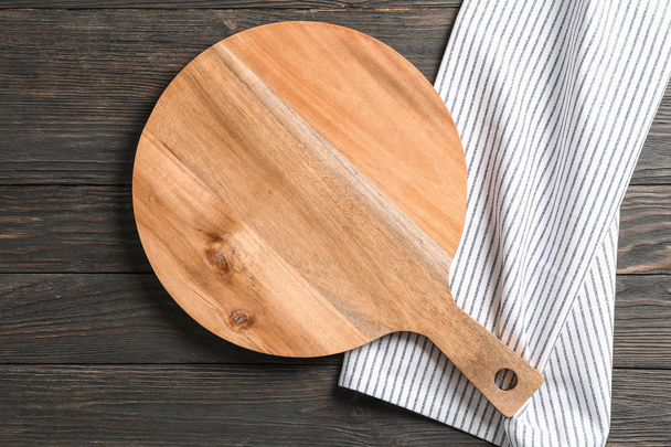 Cutting board with kitchen towel on wooden background, space for - Photo, Image