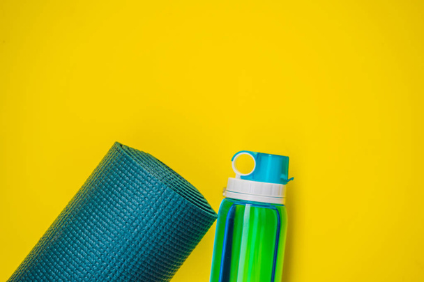 Everything for sports turquoise, blue shades on a yellow background. Yoga mat, sport shoes sportswear and bottle of water. Concept healthy lifestyle, sport and diet. Sport equipment. Copy space - Photo, image