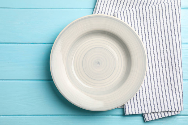 Kitchen towel with plate on wooden background, top view - 写真・画像