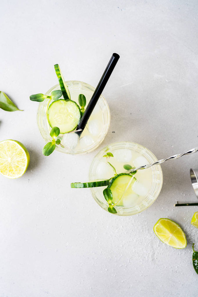  two glasses of mojito lemonade with cucumber and lime slices on white stone background - Foto, imagen