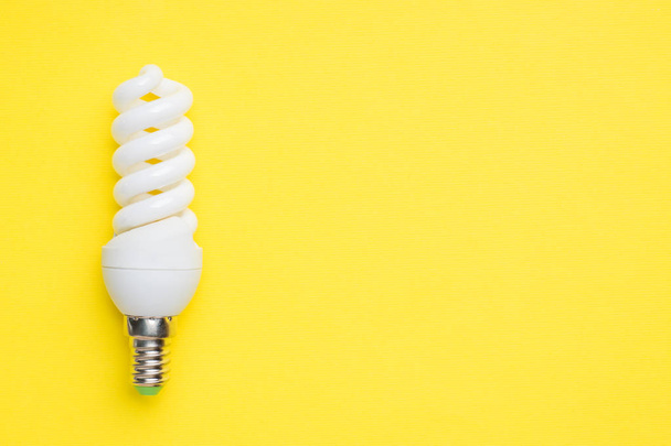 White light bulb on bright yellow background with copy space Selective focus. - Фото, изображение
