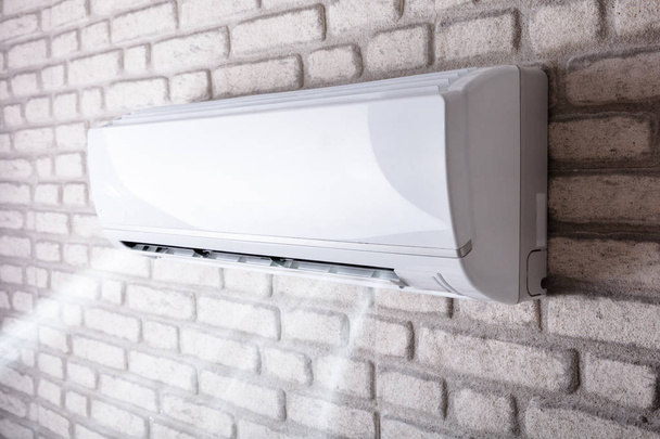 White Air Conditioner Blowing Cold Air On Brick Wall In Living Room - Foto, Bild