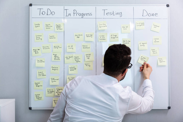 Side View Of Businessman Writing On Sticky Notes Attached To White Board In Office - Foto, Imagem