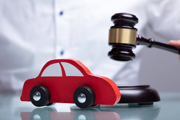 Close-up Of A Small Red Car In Front Of Judge Holding Mallet - Photo, image
