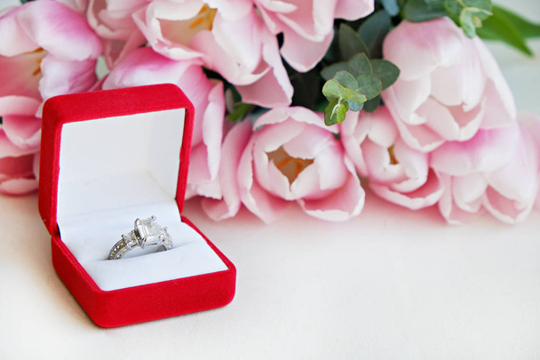 Close up composition with luxurious diamond ring and beautiful bouquet of pink tulips. - Foto, Imagem