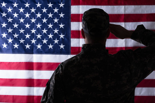 Rear View Of Military Man Saluting Us Flag - Фото, изображение