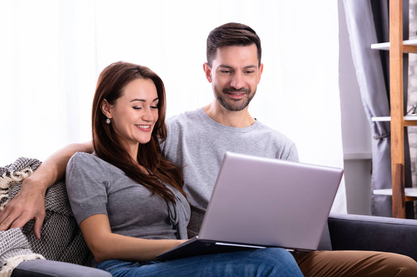 Smiling Young Couple Working Laptop At Home - Foto, Imagen