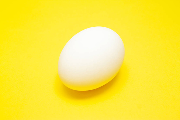 White easter egg on yellow background in center. Design, visual art, minimalism - Photo, Image