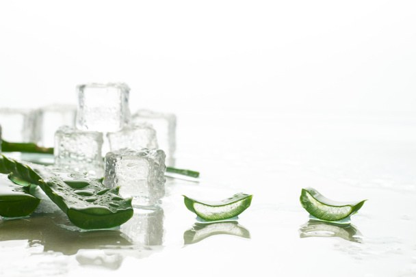Aloe leaf and ice cubes on a light background. Refreshing and cooling for skin, anti-thirst drink. - Photo, Image