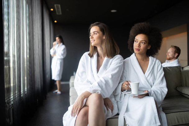 Attractive young women drinking coffee at spa center - Foto, Bild