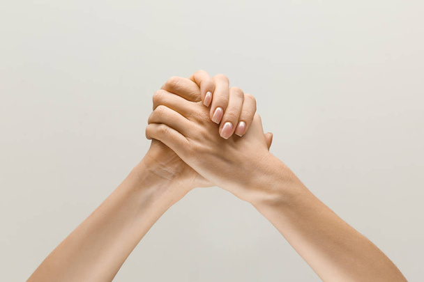 loseup shot of human holding hands isolated on grey studio background. - Foto, imagen