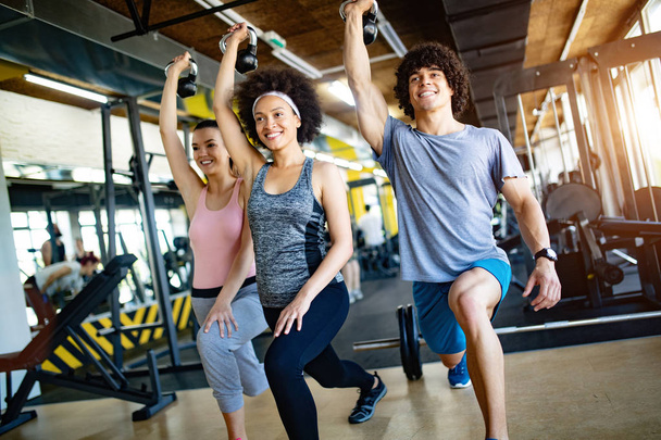 Picture of cheerful young fitness team in gym - Фото, изображение