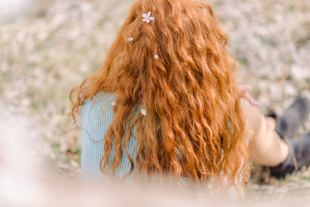 Curly red hair with white blossom, back view. - Foto, Bild
