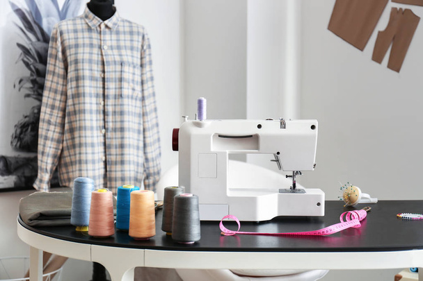 Máquina de coser con accesorios en el lugar de trabajo del sastre en el taller
 - Foto, Imagen