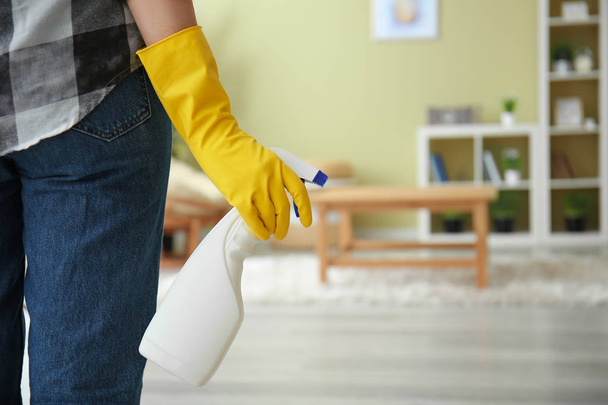 Woman with bottle of detergent in room - Foto, afbeelding
