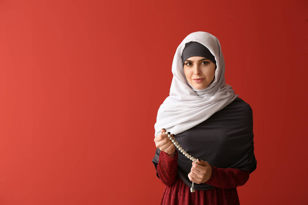 Muslim woman with tasbih on color background - Photo, Image