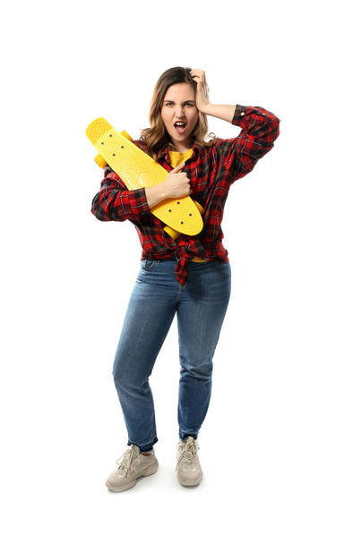 Portrait of emotional young woman with skateboard on white background - Photo, Image