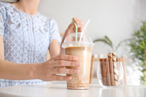 Woman drinking tasty frappe coffee at table - Foto, Imagen