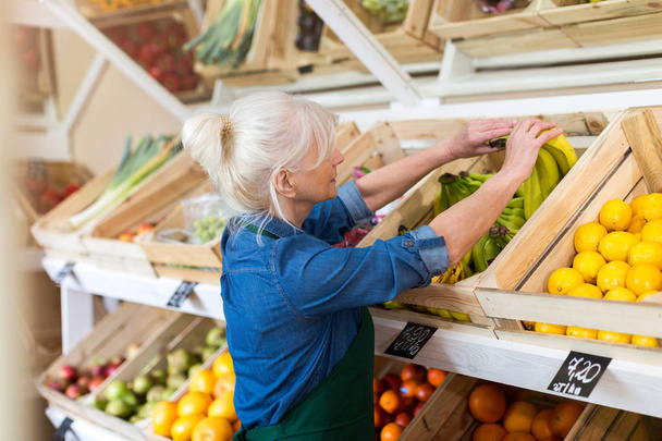 Senior woman working in small grocery store - Foto, imagen