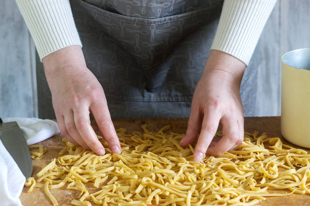 A woman makes homemade noodles from flour, eggs and salt. Rustic style. - 写真・画像