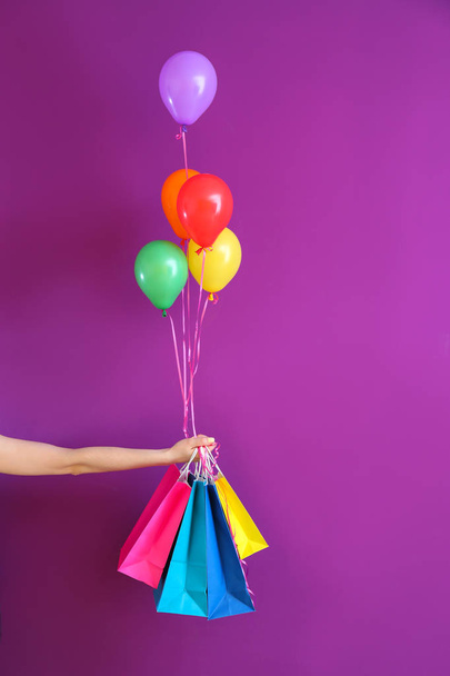 Female hand with gifts and air balloons on color background - Фото, зображення