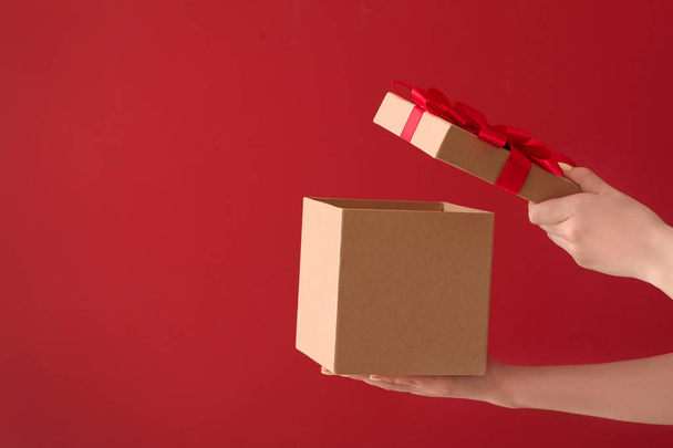 Жіночі руки з подарунковою коробкою на кольоровому фоні
 - Фото, зображення