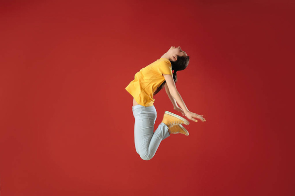 Jumping young woman against color background - Fotografie, Obrázek