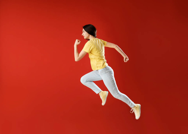 Running young woman against color background - Фото, изображение