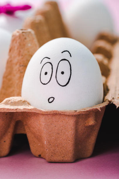 selektivní zaměření vajíčka se zaskočením na tváři vaječného kartonu - Fotografie, Obrázek