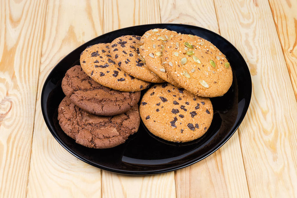 Divers cookies goutte à goutte sur plat noir sur la table en bois
 - Photo, image