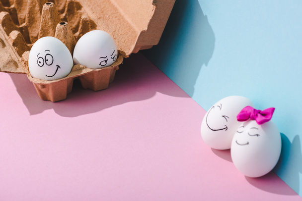œufs avec des expressions de visage souriantes et en colère sur bleu et rose avec espace de copie
 - Photo, image
