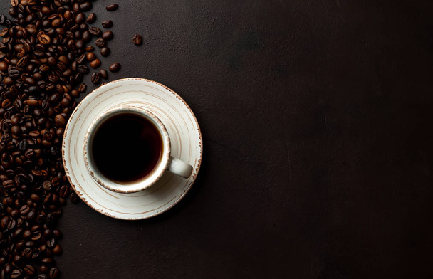Fresh cup of coffee on black stone background with coffee beans  - Фото, изображение