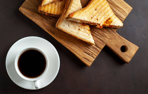 Panini alla griglia serviti con tazza di caffè sul tagliere di legno
 - Foto, immagini