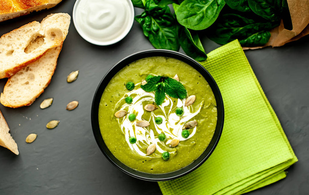 Zuppa di crema verde di spinaci e broccoli servita con semi di zucca e yogurt greco su sfondo di legno
 - Foto, immagini