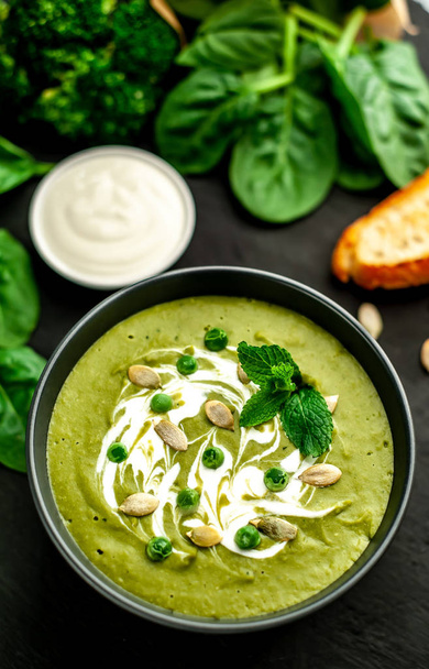 Green cream soup of spinach and broccoli served with pumpkin seeds and greek yogurt on wooden background - Photo, Image