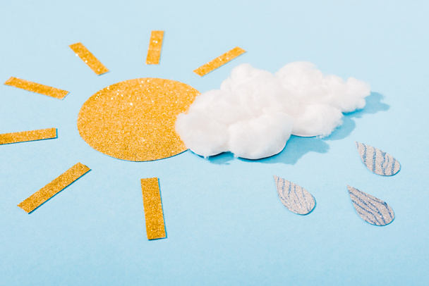 блестящая бумага солнце и сладкая вата облако с серебряными капельками дождя на голубой
 - Фото, изображение