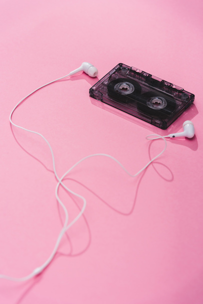 plastic vintage audio cassette with earphones on pink, music concept - Zdjęcie, obraz