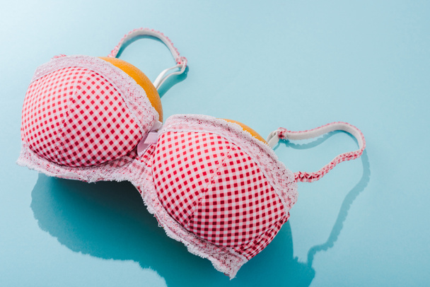 bra with two oranges on blue, breasts concept - Photo, Image