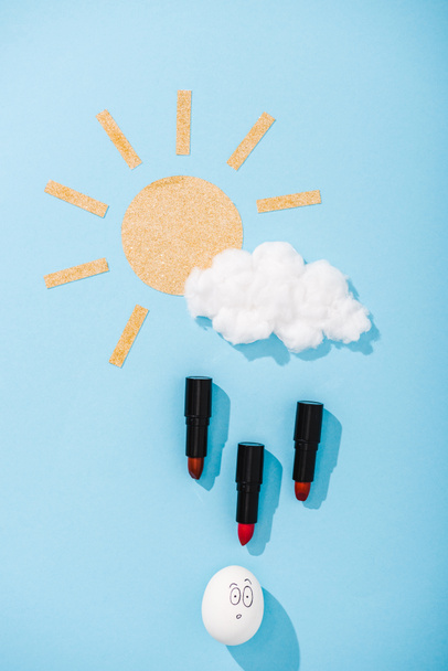 kağıt güneş üst görünümü, pamuk şeker bulut, sürpriz yüz ifadesi ile yumurta ve mavi Ruj yağmur damlaları - Fotoğraf, Görsel