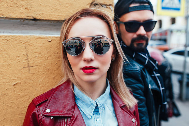 Sexy couple in leather jacket and sunglasses posing over wall in city - 写真・画像