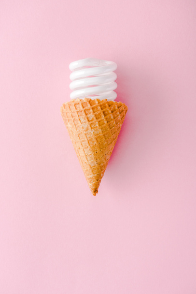 pohled na energeticky úsporou žárovku v zmrzlinovém kuželu izolované na růžových - Fotografie, Obrázek