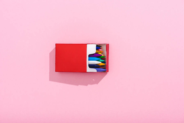 вид сверху разноцветных карандашей в красном пакете сигарет на розовом с копировальным местом, концепция курения
 - Фото, изображение