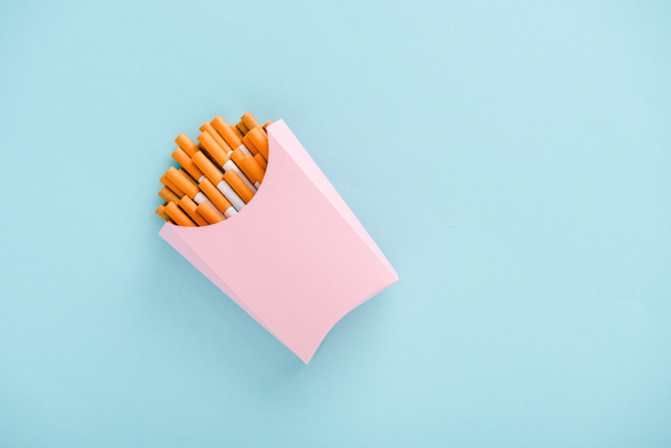 vista superior de cigarrillos envasados en caja de papel aislada en azul con espacio para copiar, concepto de papas fritas
 - Foto, Imagen