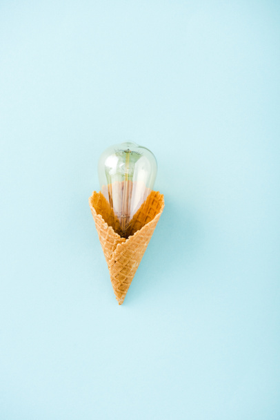 top view of glass lightbulb in ice cream cone isolated on blue - Photo, Image