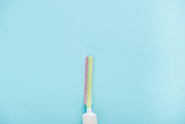 コピースペースで青に隔離されたカラフルなキャンディを噛む歯磨き粉チューブのトップビュー - 写真・画像